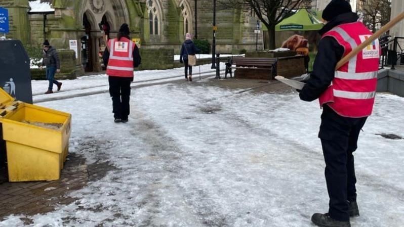 Council workers in high-vis tabbards clearing snow