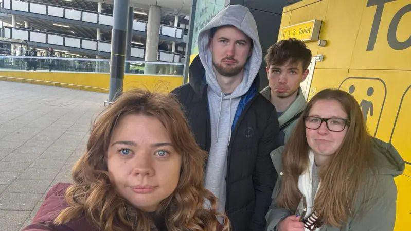 Four young people, two boys two girls, stood at Gatwick Airport for a selfie