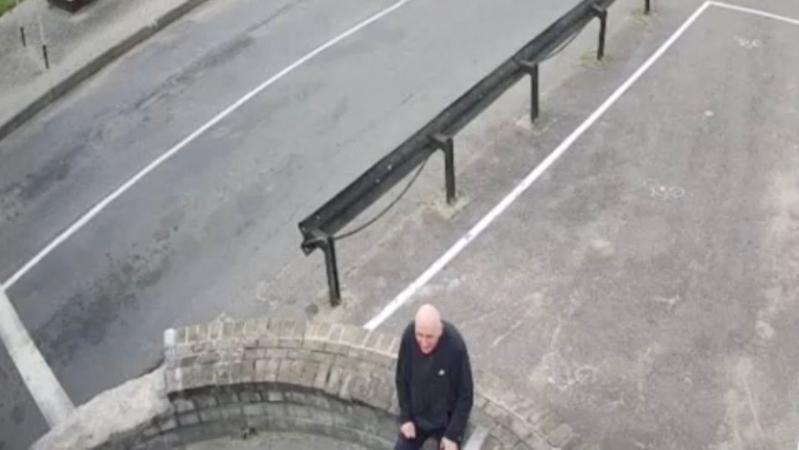 A man in a black top sits on his own at a border crossing