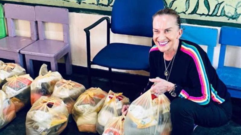 Clare with bags of donated supplies in a school corridor smiling for the camera.