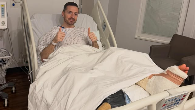 Midfielder Jack Grealish posing in a hospital bed with a bandaged foot