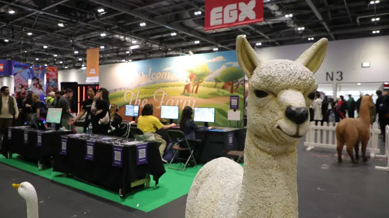 People sit at computers set up behind statues of farm animals, with a model llama prominently in frame.