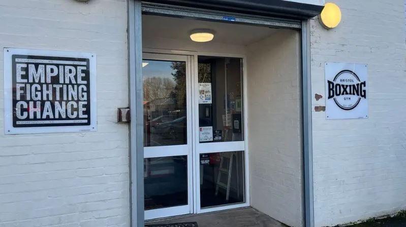 The door to Empire Fighting Chance boxing gym. There is a sign with the gym name on next to the door. 