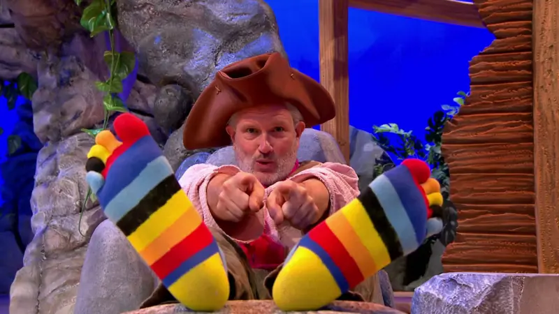 Sandy is pointing at the camera with his feet in the air.