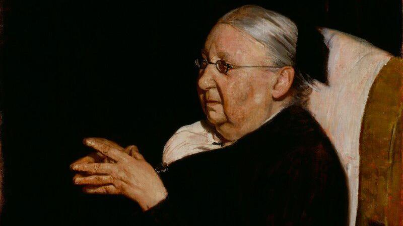 An oil painting of an elderly woman in black with her hands clasped together. 