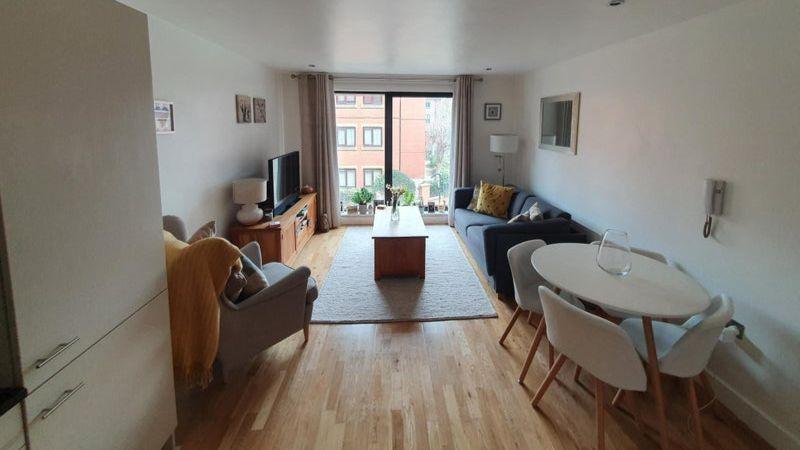 A small modern flat containing a grey chair, white table and four chairs and coffee table.