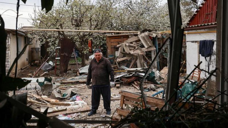 A resident stands on a backyard of his house damaged during a Russian drone strike, amid Russia's attack on Ukraine, in Odesa, Ukraine April 16, 2025
