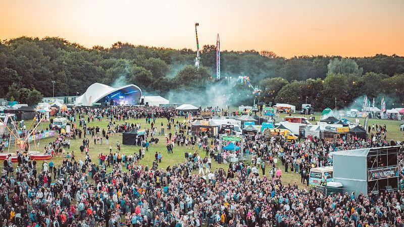 Hundreds of people attending Godiva Festival. A stage and food stalls can be seen in the background.