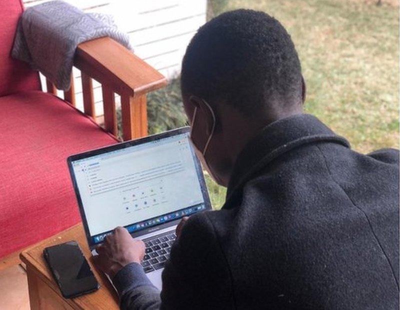 David, a Kenyan academic writer with a mask working on a laptop.