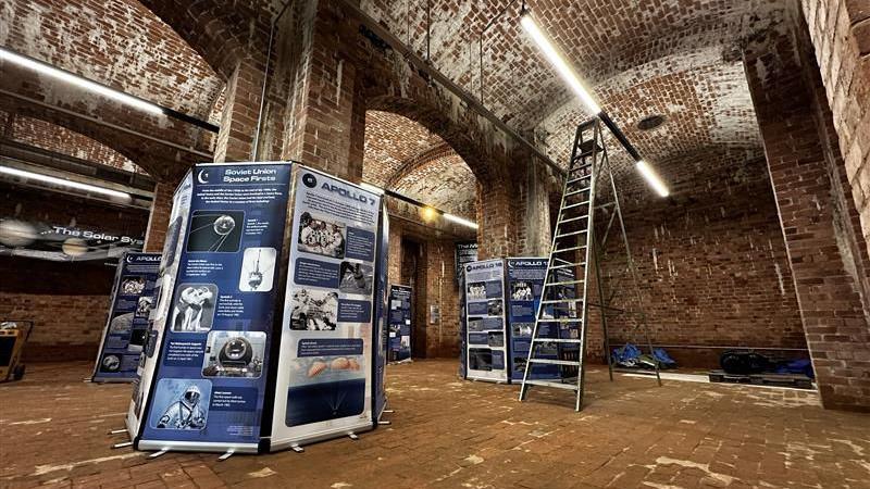 Blue banners with information about space travel in the old Victorian reservoir which has red brick walls, ceiling and floor.