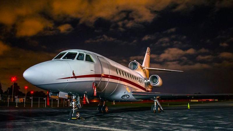 Falcon 900B business jet standing on the tarmac at an airport at night