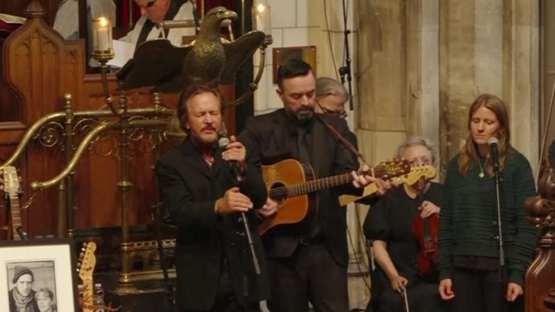 Hansard's former partner Markéta Irglová performing alongside Pearl Jam singer Eddie Vedder in a church ceremony. Several other musicians ar eplaying guitar beside them