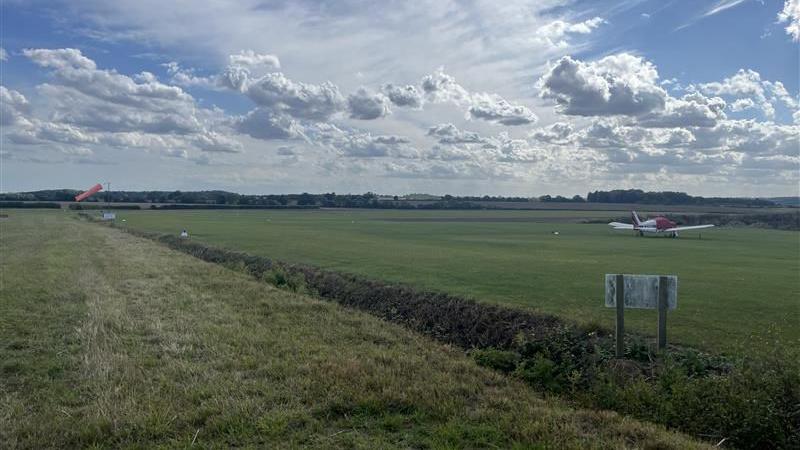 A wide angled shot of Elmsett Airfield. A plane can be seen in the distance.