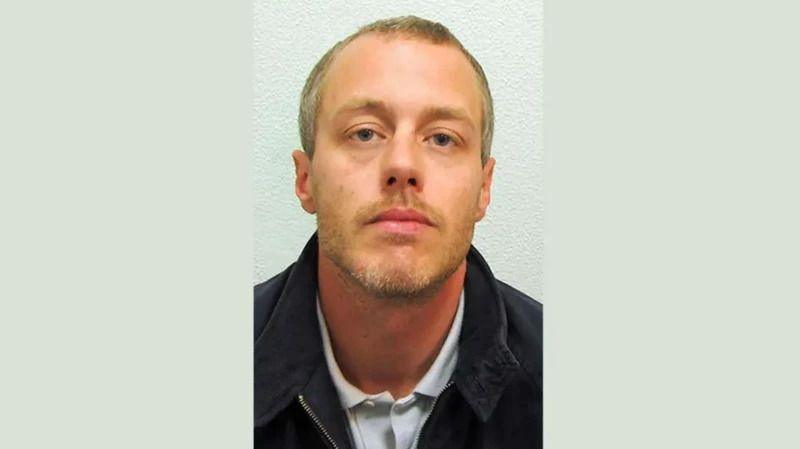 David Norris mugshot. He wears an unzipped black jacket over a white polo shirt. He has short blonde hair and facial hair.