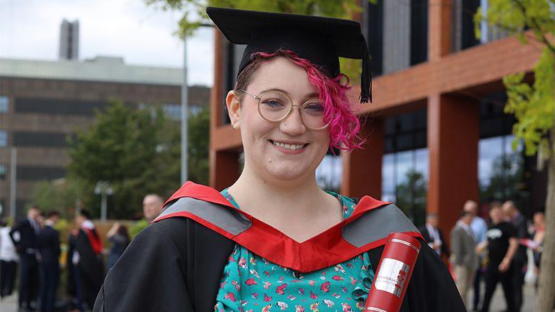 Opal Raine smiling while wearing a graduation cap and gown