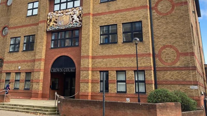 St Albans Crown Court: a yellow and orange brick building. A set of stone steps is leading to the entrance. Above the entrance is a sign saying "Crown Court".