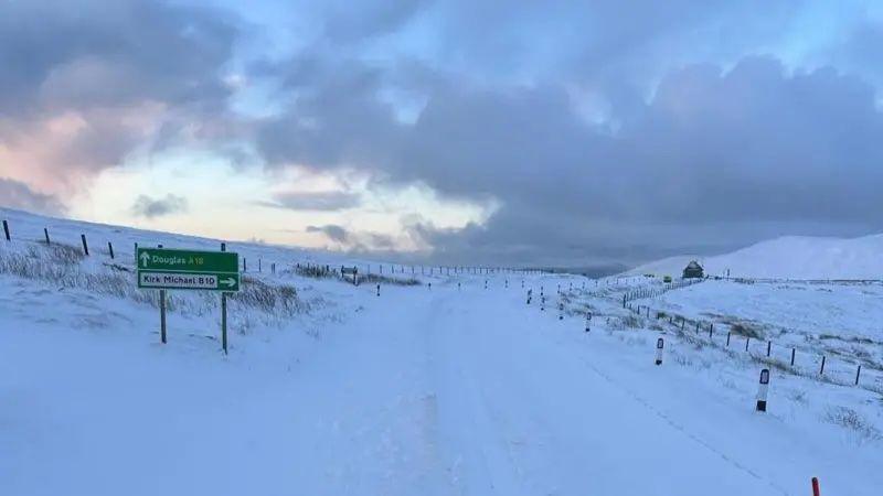 The mountain covered in snow, with a sign pointing to Kirk Michael. 