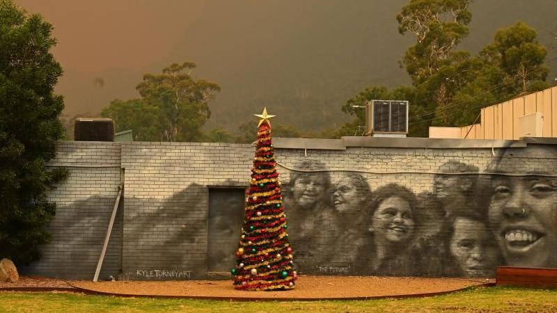 A Christmas tree sits against a backdrop of blackened sky 