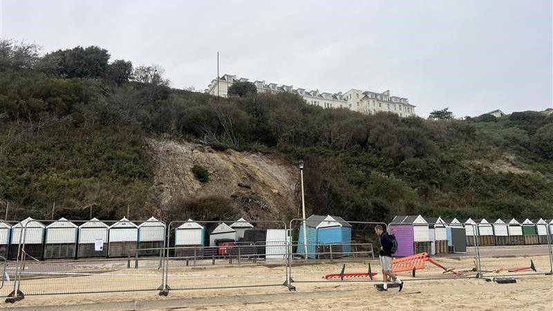 multiple beach huts crushed under a landslide