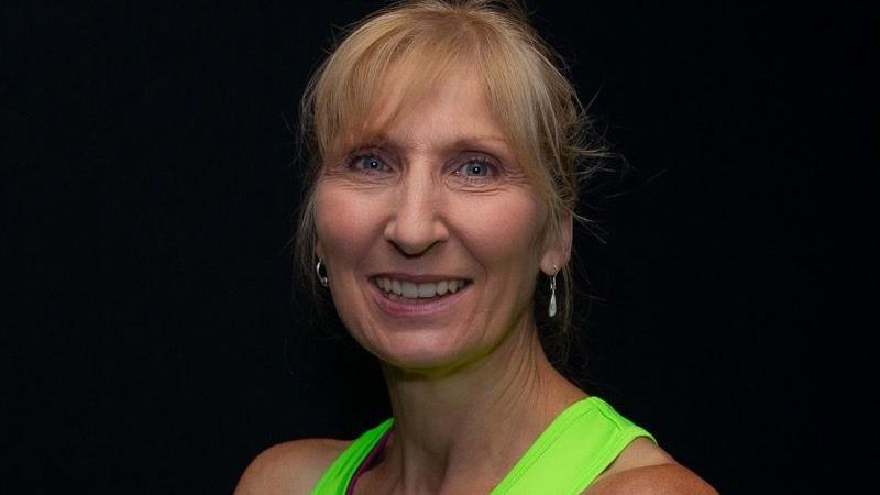 Ruth Dawson wears a green tank top and poses with her arms crossed 