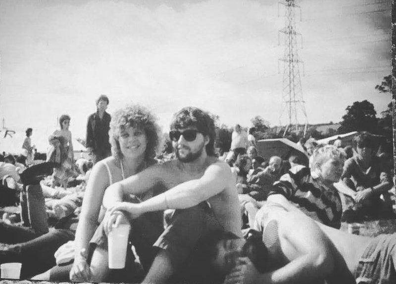 Man and woman sitting on the ground surrounded by a crowd of festival-goers