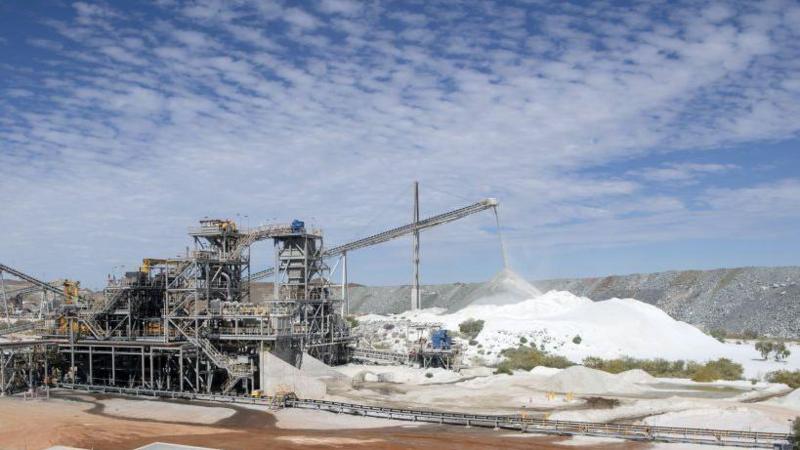 Photo of a rare earth mine with factory equipment and piles of white material