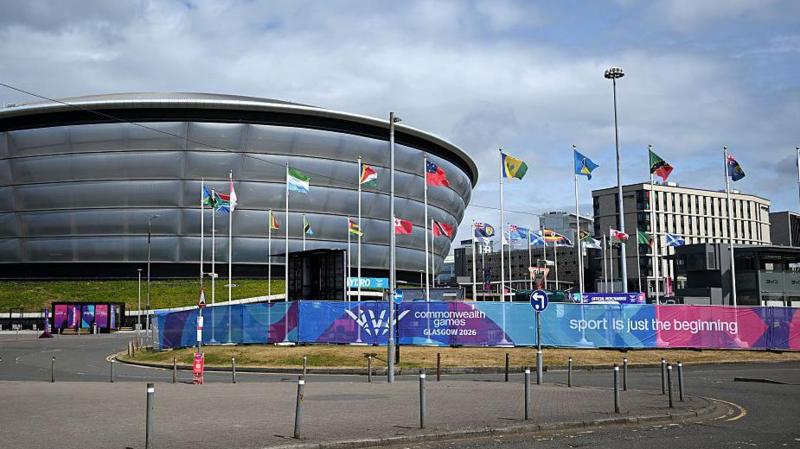 A view of the OVO Hydro building. Several poles with flags of commonwealth countries are set up outside, along with banners advertising the commonwealth games, saying sport is just the beginning.