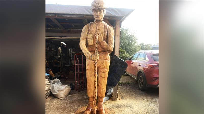 Wooden sculpture of a soldier stood in a yard