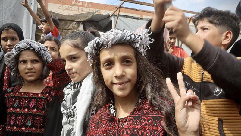 Palestinians, including children, gathered in the city of Khan Yunis celebrate after the announcement of the ceasefire agreement in Gaza on October 09, 2025