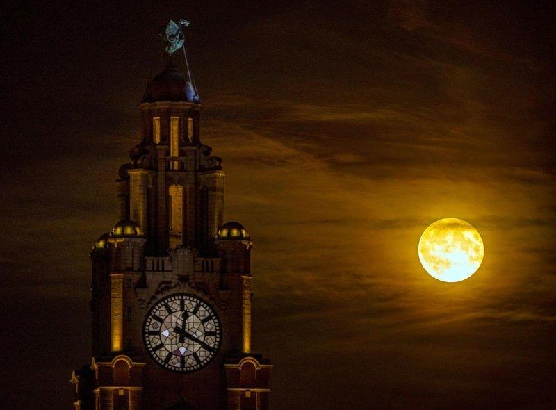 The strawberry moon rises behind the Liver Building in Liverpool.