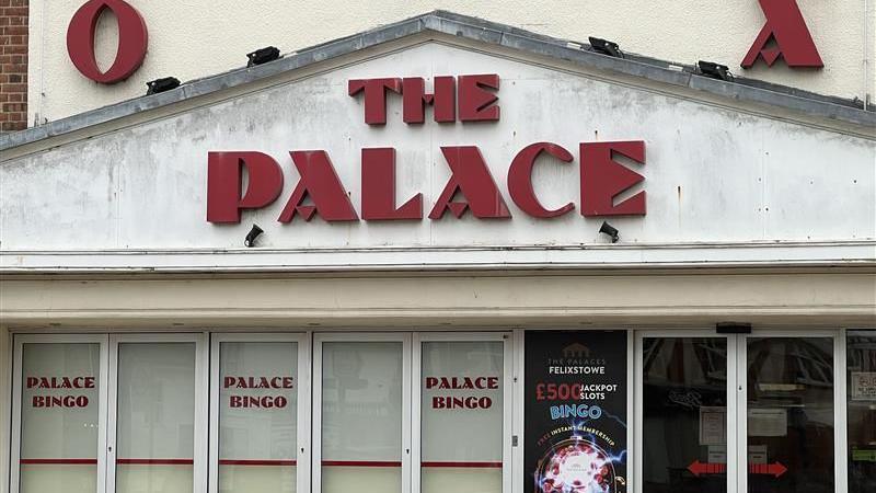 A close up of the entrance into the Palace Cinema. The cinema's name is written in large red letters on a white background above windows.