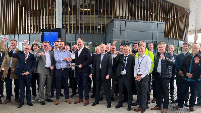 A large group of men cheering in front of the new transport hub