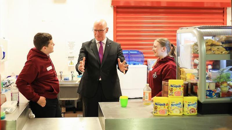 John Swinney at a school canteen counter