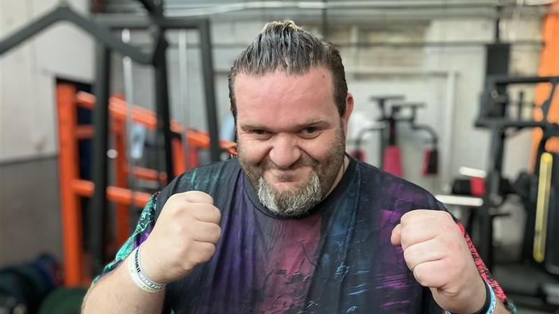 Ben Bretts, a man wearing a black t-shirt with a multi-coloured pattern on it, is holding his hands up in fists, mimicking a boxing pose.