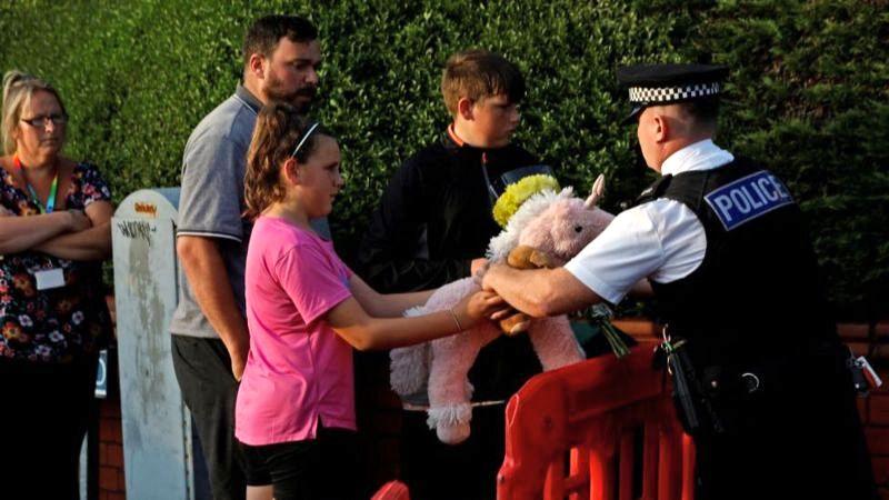 child giving cuddly toy to policeman