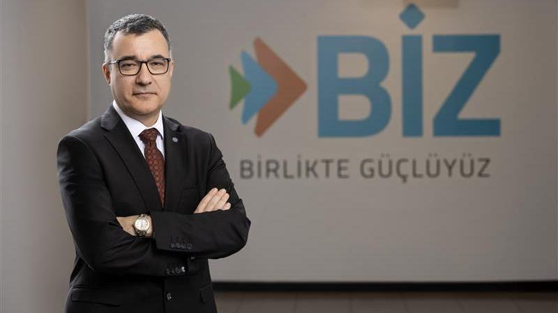 Ihsan Tolga Akar, wearing a dark suit, stands in front of a logo which says BIZ. He is wearing glasses, has his arms folded and has short grey hair. 