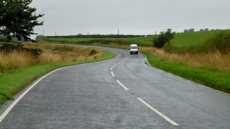 A winding road in south west Scotland with a van in the distance wending its way through green countryside