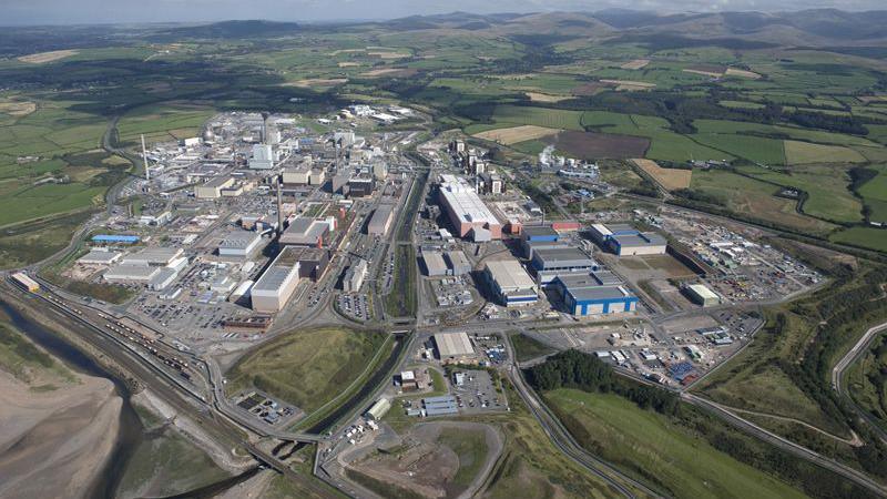 An aerial image of Sellafield. The large site, which looks like an industrial estate with several buildings, roads and car parks, is surrounded by green fields.