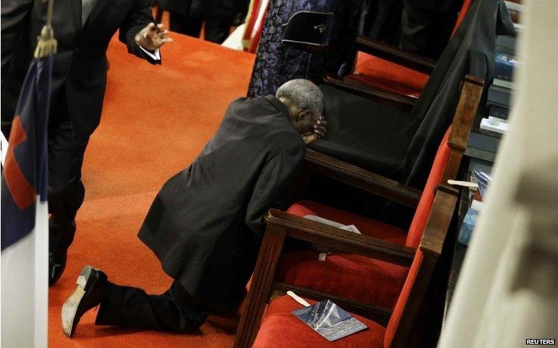 A parishioner prays at the empty seat of the Rev. Clementa Pinckney before services at the Emanuel African Methodist Episcopal Church in Charleston, South Carolina, June 21, 2015