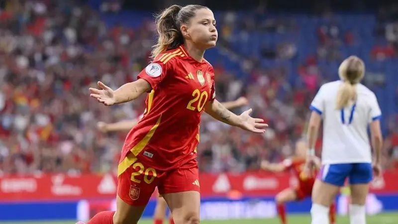 Claudia Pina runs with her arms wide celebrating scoring a goal against England. She wears a red and yellow Spain kit and her hair is in a pony-tail.