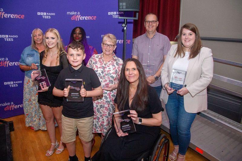 A group shot of all of the winners smiling and holding their trophies.