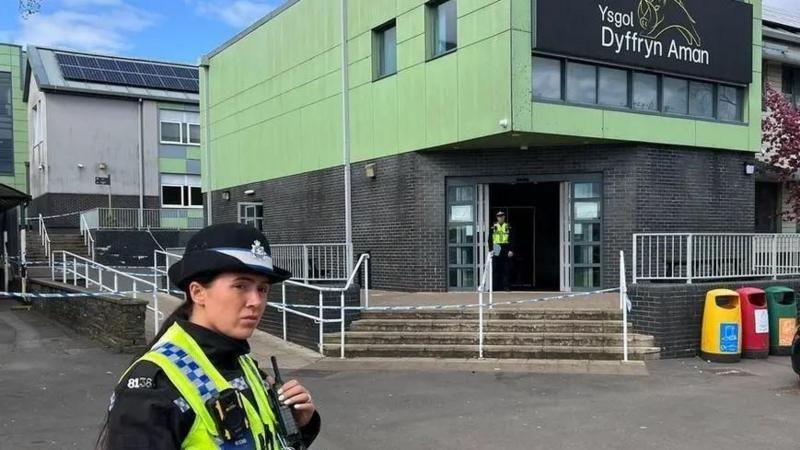 Police officer stands in front of a school which is in lock down