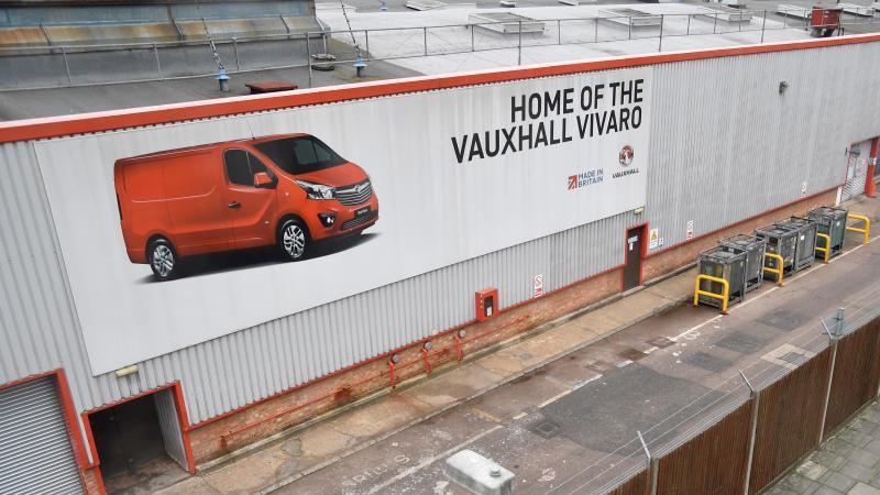 A sign outside Vauxhall's Luton plant in Luton, on 4 April, 2018, showing a red Vivaro van, on a big grey building with a fence to the right.