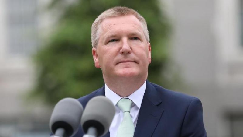 Michael McGrath standing in front of microphone 