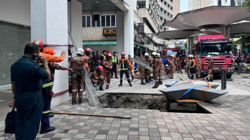 Malaysian rescue workers try to enter a sinkhole in Kuala Lumpur to save a woman who was suddenly swallowed up by the pavement.