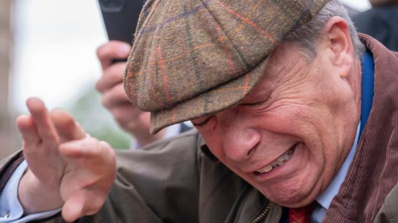 Nigel Farage shielding his face