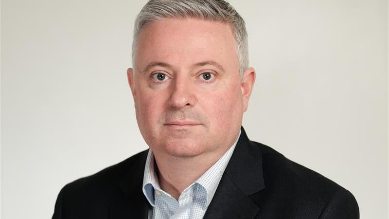Current ceo of EPUT Paul Scott. He is looking directly at the camera and you can see his head and shoulders. He is wearing a black suit jacket and checked white and pale blue shirt. He has grey hair.
