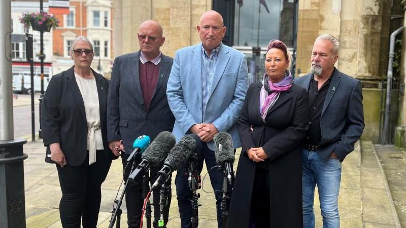 Two women and three men in front of microphones outside the Sessions House