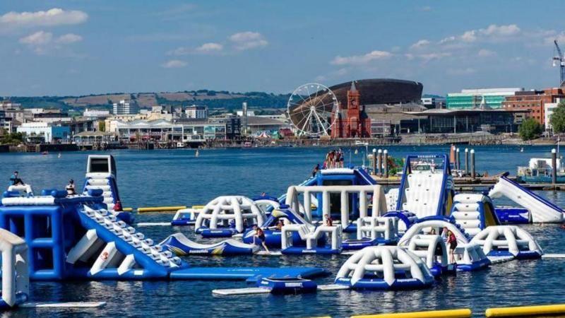 Aqua park's blue and white inflatable obstacle course on the water at Cardiff Bay