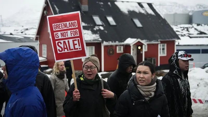 A woman holds a sign that says Greenland is not for sale